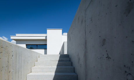 Contemporary concrete staircase leading to a minimalist building under a clear blue sky.