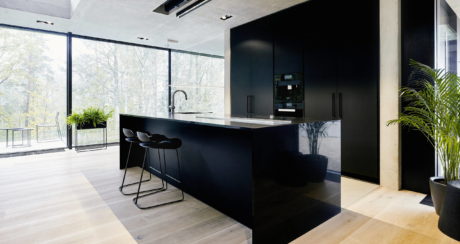 Modern kitchen interior with black cabinetry, bar stools, and floor-to-ceiling