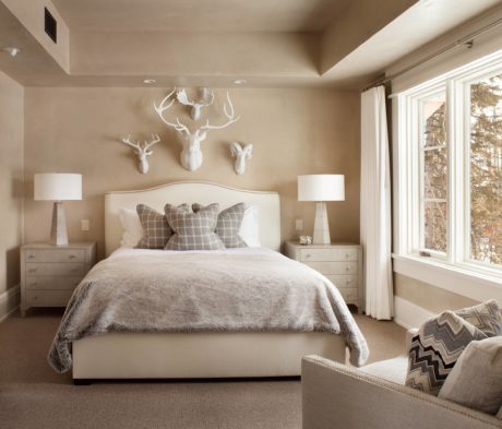 Neutral-toned bedroom with a large bed, antler decor, and matching night