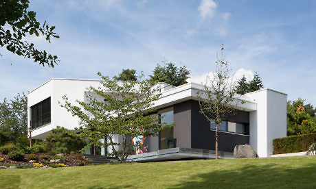 Contemporary two-story home with flat roofs and a landscaped garden.