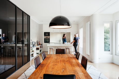 Contemporary dining room with large wooden table and black dome light fixture.