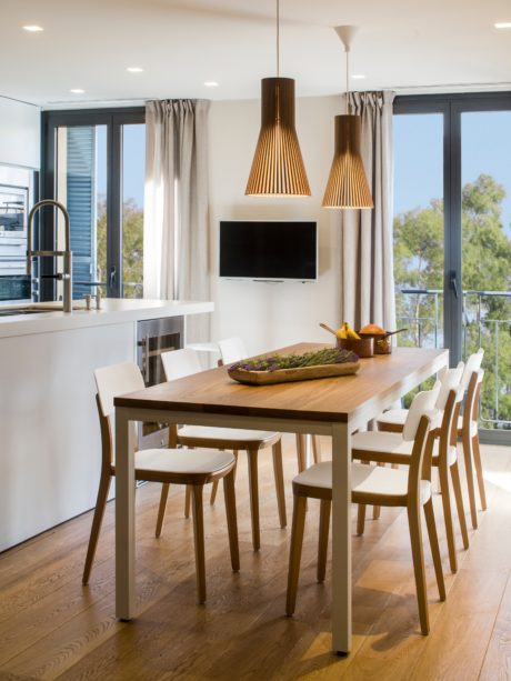 Contemporary dining room with wooden table, pendant lights, and large windows.