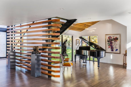 Modern interior with wooden slat staircase and grand piano.