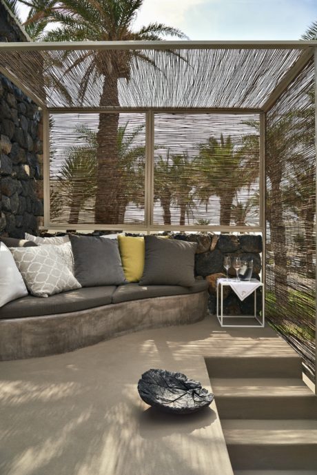 Contemporary outdoor lounge with cushioned seating and palm view.
