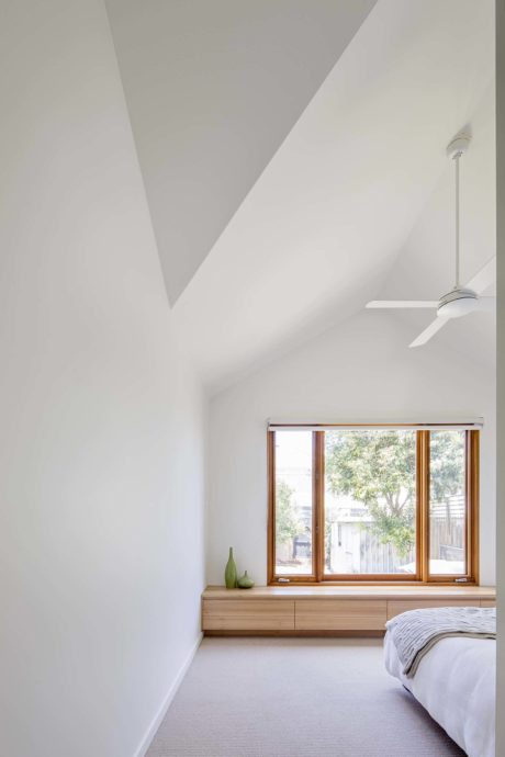 Minimalist bedroom with sloped ceiling, large window, and ceiling fan.