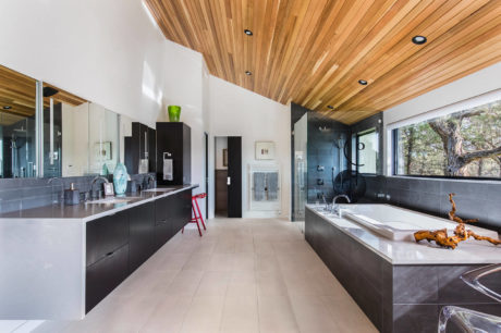 Sleek bathroom with wood ceiling, glass shower, and white tub.