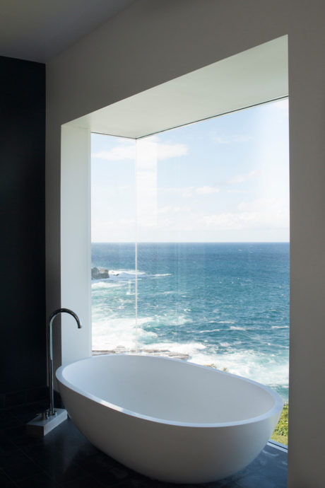 Sleek bathroom with ocean view through a floor-to-ceiling window and a