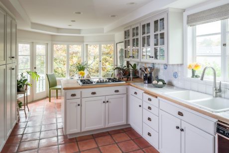 Bright kitchen with white cabinetry and terracotta floor tiles.