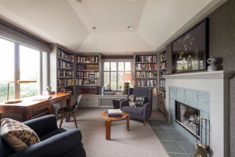 Contemporary home office with bookshelves and fireplace.