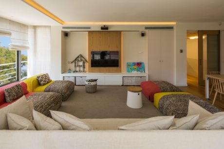 Contemporary living room with colorful couches and a central TV.