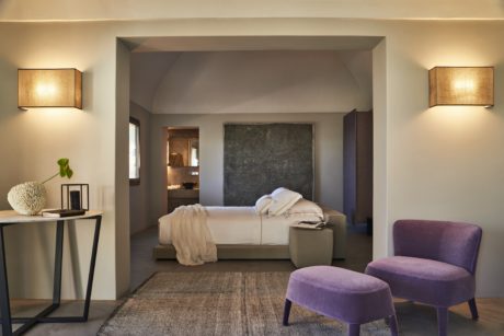 Minimalist bedroom with arch doorway, modern furniture, and warm lighting.