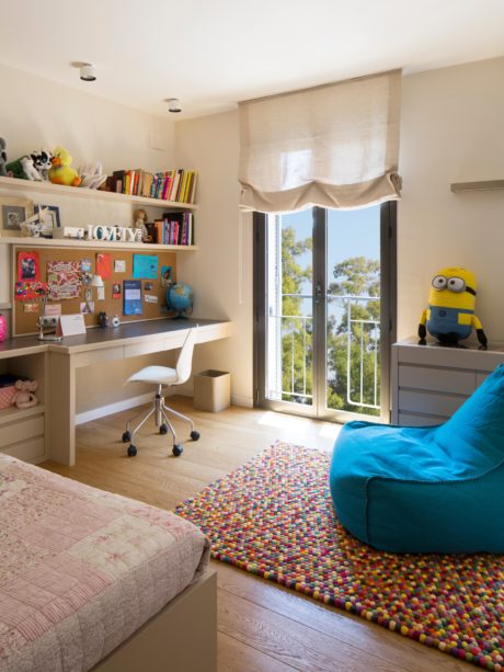 Cozy bedroom with a study area, colorful rug, and plush beanbag.