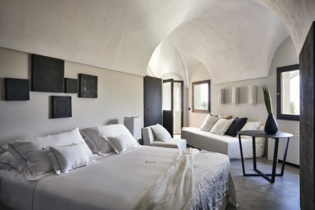 Minimalist bedroom with arched ceilings and neutral tones.