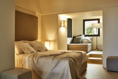 Modern bedroom with a neatly made bed, side lamps, and warm lighting.