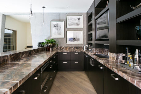 Modern kitchen with marble countertops and dark wood cabinets.