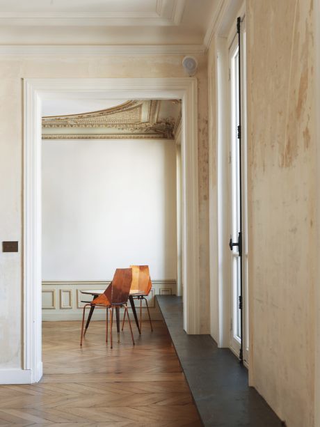 View of a classical room with herringbone flooring and decorative ceiling through an open