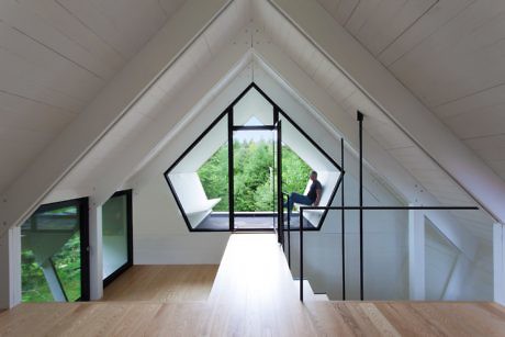 Modern attic room with geometric windows and a person sitting by the glass.