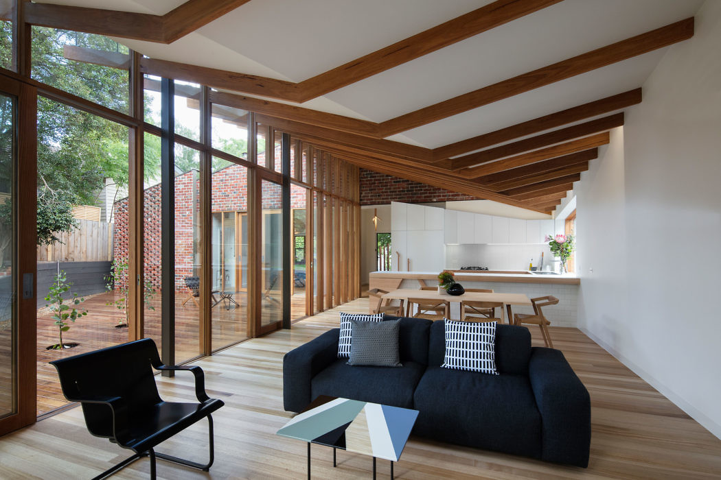 Modern living room with large windows, wooden beams, and minimalist furniture.