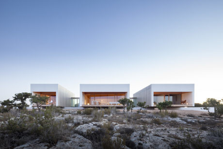 Modern minimalist buildings in a desert landscape at dusk.