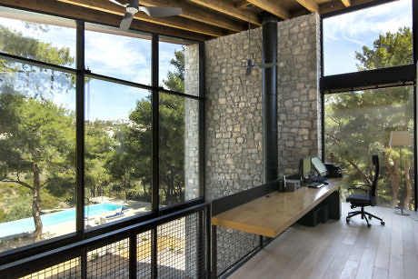 Contemporary home office with stone wall, large windows, and pool view.