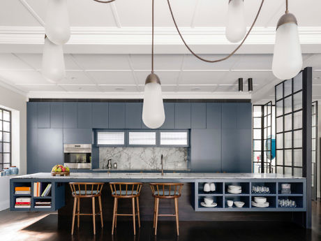 Modern kitchen with blue cabinets, marble backsplash, and pendant lights.
