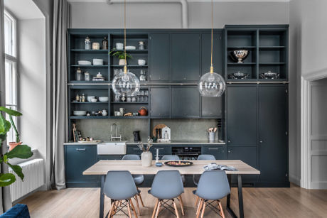 Modern kitchen with dark cabinetry and dining area with blue chairs.