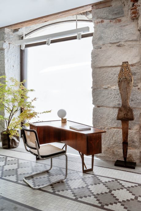 Chic office space with exposed brick, wooden desk, and a sculptural art