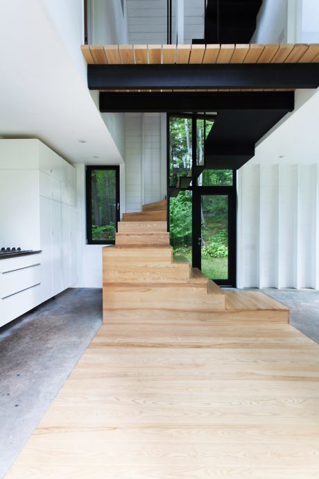 Contemporary staircase with light wood steps and black metal details in a bright space.