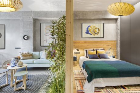 Modern living room and bedroom with concrete walls and wooden accents.