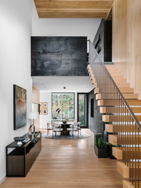 Modern home interior with wooden stairs, high ceilings, and minimalist decor.
