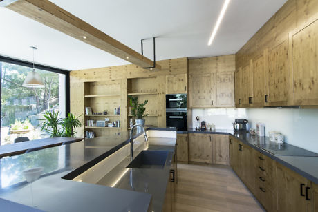 Modern kitchen with wooden cabinets, stainless steel countertops, and pendant lighting.