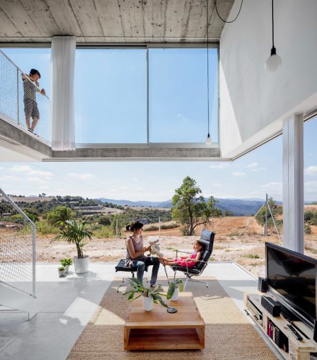 Modern interior with large window views, high ceiling, and two people relaxing.