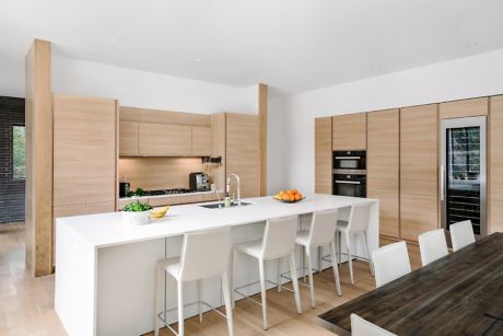 Modern kitchen with wood cabinets, a white island, and bar stools.