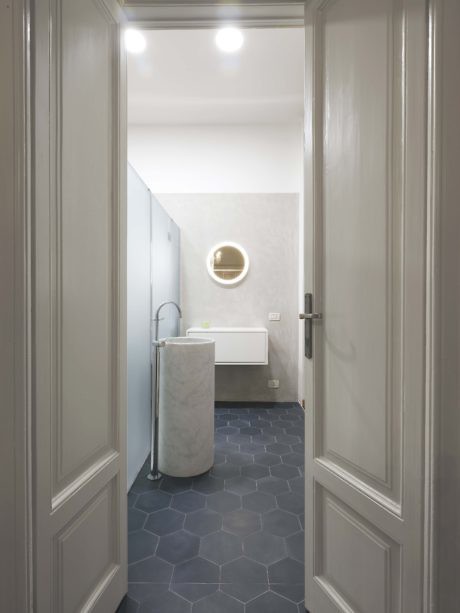 Modern bathroom with hexagonal tiles, round mirror, and white sink.