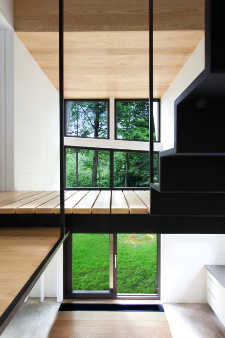 Modern interior with black stairs, wooden floors, and a view of greenery through