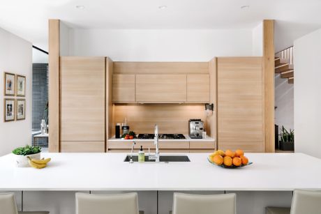 Modern kitchen with wooden cabinets and white countertops with fruit bowls.