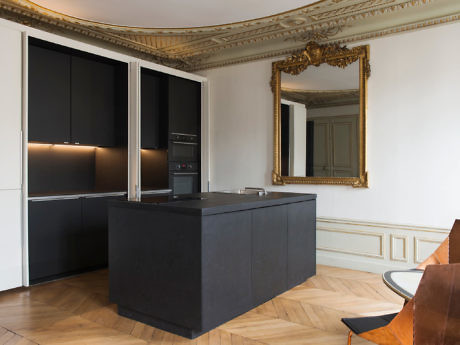 Modern kitchen with black cabinets in a room with classic ornate molding and a large