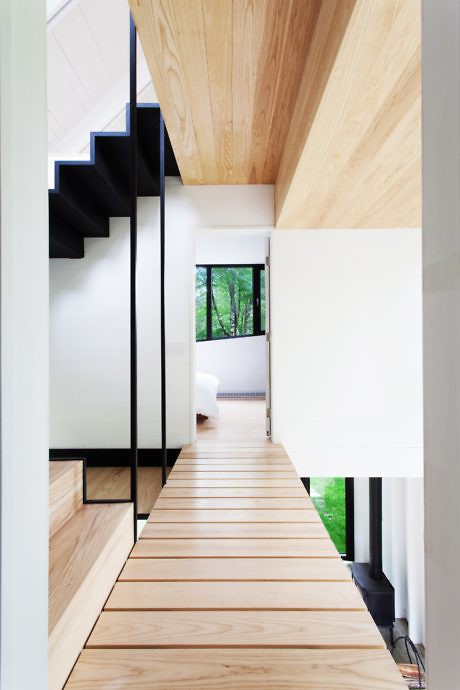 Modern hallway with wooden floors, white walls, and a black staircase.