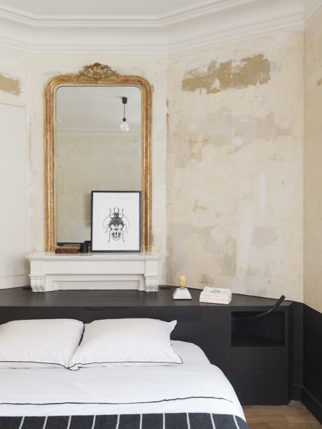 Elegant bedroom with distressed walls and ornate gold mirror.
