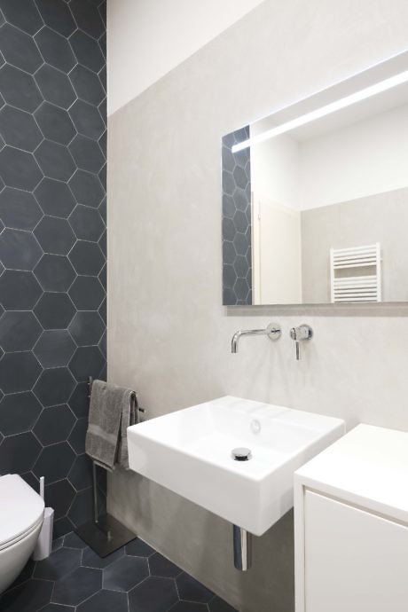 Sleek bathroom with hexagonal tile wall and illuminated mirror.