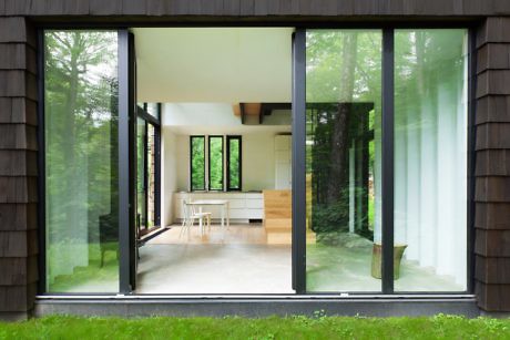 Contemporary house with large windows offering view into minimalist interior.