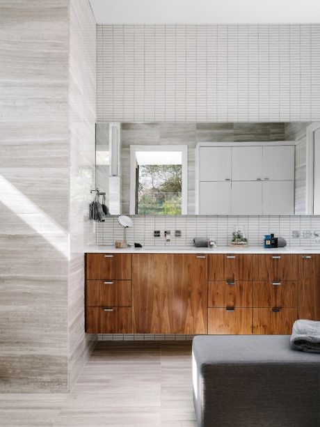 Contemporary bathroom with wood vanity and tiled walls.