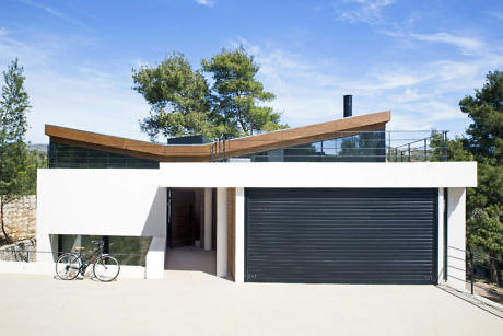 Modern house with curved roof, large garage door, and bicycle parked outside.