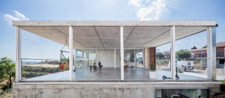 Modern house with large porch, glass walls, and mesh screen.