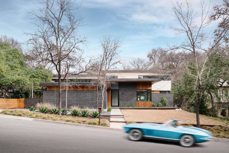 Modern house with flat roof and wooden accents, a car passing by.