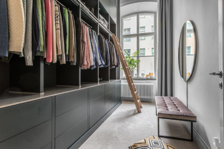 Modern walk-in closet with organized clothes, ladder, and mirror.