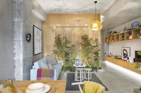 Modern cozy living room with wooden slats, plants, and pendant light.