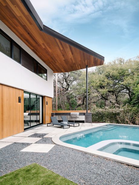 Modern house exterior with pool and wooden overhang.