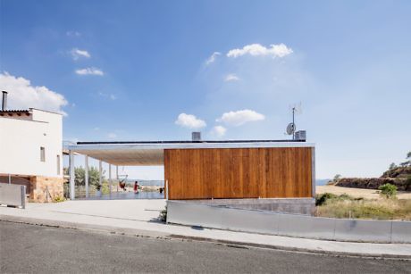 Modern house with wooden facade and flat roof against a blue sky.