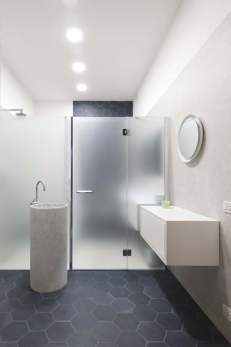 Contemporary restroom with frosted glass shower, marble sink, and hexagonal tiles
